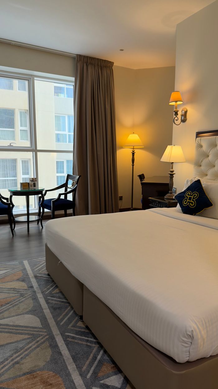 A well-appointed hotel room featuring stylish furniture, ambient lighting, and large windows.